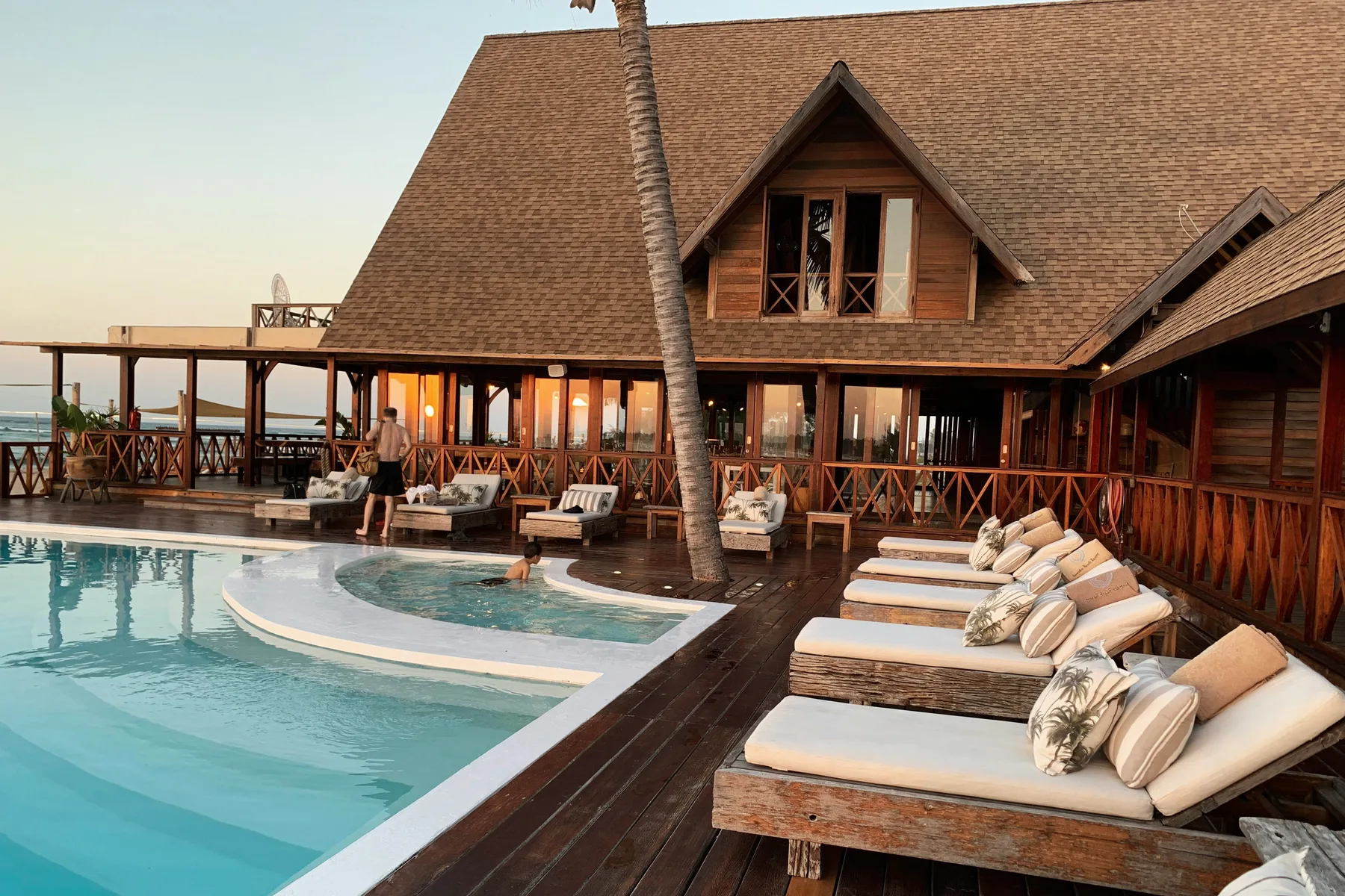 Warm wooden tropical resort overlooking a curved swimming pool