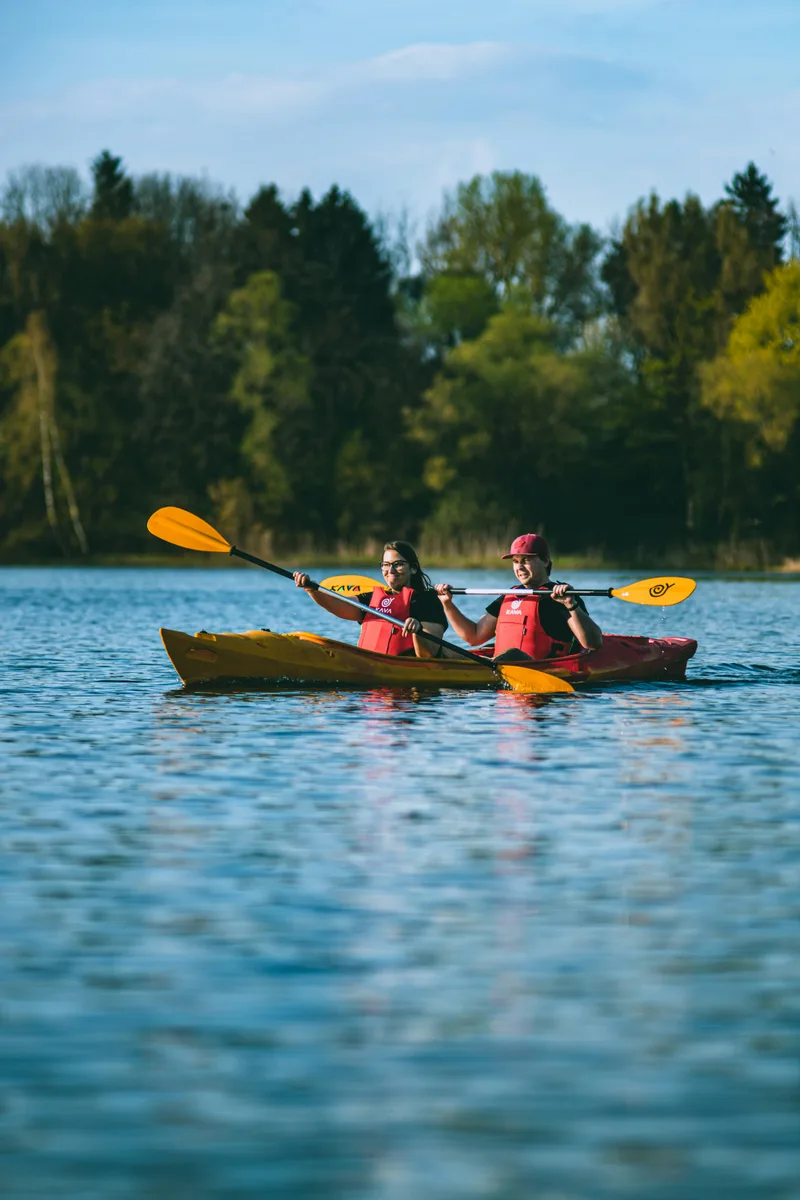 Two people kayaking together across a calm blue lake