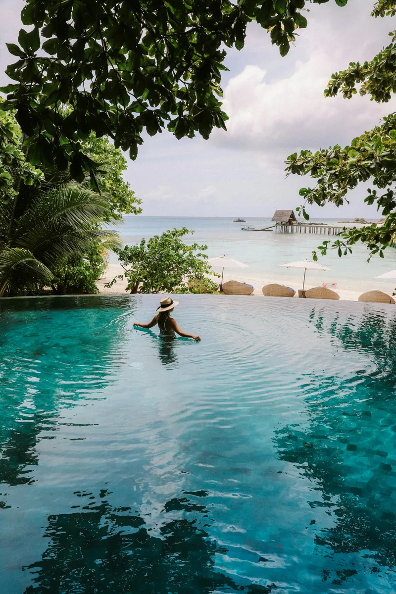 Guest enjoying an infinity pool facing a quiet tropical beach